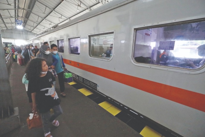 BALIK: Serombongan penumpang melintasi gerbong kereta api di Stasiun Kota Kediri kemarin. Arus penumpang kereta diperkirakan mengalami puncaknya hari ini. (Foto: Wahyu Adji)