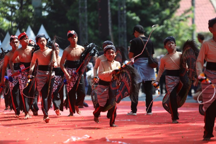 SEMARAK: Peserta Festival Jaranan Jawa kelompok SD berlari memasuki area lomba sebelum memeragakan tarian. Foto bawah, Bupati Dhito membungkuk setelah menerima kuda kepang dari Abid Fadlurohman sesaat setelah acara pembukaan festival. (Foto: Wahyu Adji)