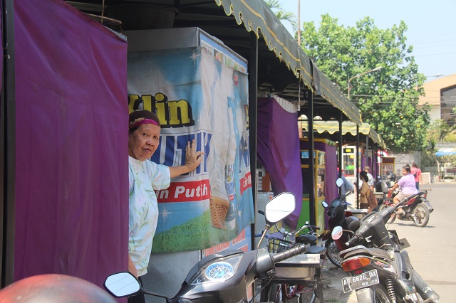 INTIP: Seorang pedagang di Alun-Alun Kota Kediri melongok dari tenda warung kemarin. Proses pemindahan ke lokasi sementara terus berlangsung seiring segera dimulainya proyek revitalisasi tempat itu. (Foto: Ayu Isma/JPRK)