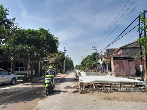 SUDAH TERATASI: Pengendara kendaraan melintas di area proyek pelebaran jalan di Desa Manyaran, Kecamatan Banyakan yang sebelumnya sempat tergenang karena pipa air bocor. (Foto: Emilia Susanti/JPRK)