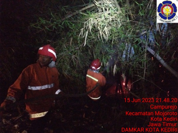 LAWAN API: Petugas pemadam kebakaran menyemprotkan air ke titik api di rumpun bambu yang terbakar di Kelurahan Campurejo, Kecamatan Mojoroto. (Foto: UPT PMK KOTA KEDIRI For JPRK)