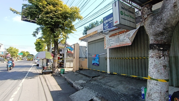 DISTERILKAN: Petugas memasang garis polisi di toko kosmetik Jalan Suwandak, Kelurahan Ditotrunan, Kecamatan/Kabupaten Lumajang. Hingga kini, polisi masih menyelidiki kasus berdarah tersebut.