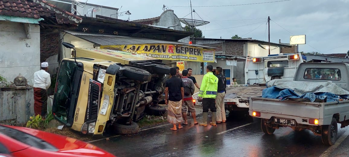 MASUK WARUNG: Bagian belakang truk boks merangsek ke dalam warung lalapan setelah terguling akibat onderdil kemudi rusak. Peristiwa ini terjadi di Dusun Mencek, Desa Serut, Panti, Jember, Sabtu (1/7).