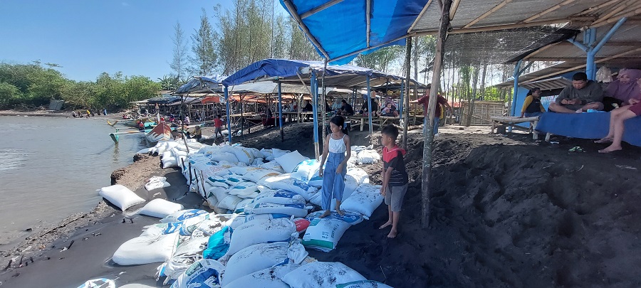 BERANTAKAN: Sejumlah sak berisi pasir dipasang ke depan warung di Pantai Cemara, Kecamatan Puger.