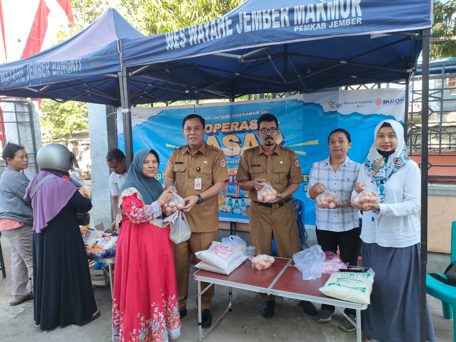 TERJANGKAU: Kepala Disperindag Jember Bambang Saputro turut serta melayani masyarakat saat belanja di Pasar Murah Kreongan, kemarin (18/7).