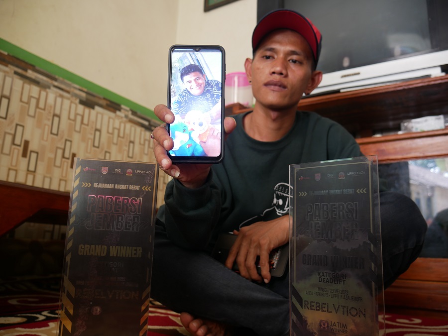TINGGAL KENANGAN: Hendrik menunjukkan foto kakaknya, Justyn Vicky, di rumah Ajung, Kalisat, kemarin. Sang kakak meninggal dunia setelah mengalami kecelakaan kerja di pusat kebugaran di Bali