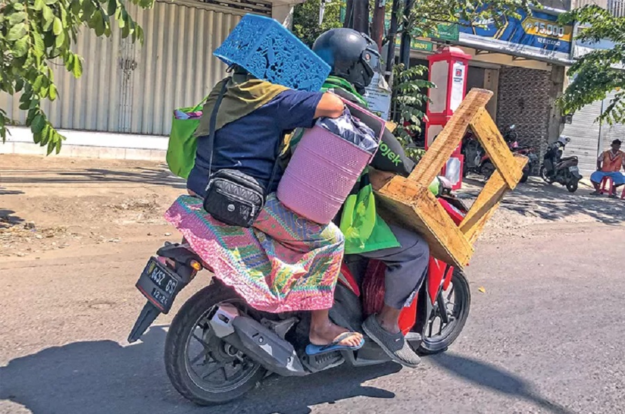 Seorang penumpang naik ojek online&nbsp; (ojol) memakai helm keranjang, beberapa waktu lalu, pengalaman seperti ini terkadang bikin kesal ojol. (Dipta Wahyu/Jawa Pos)