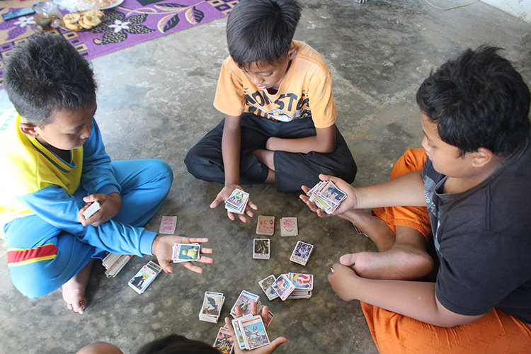 FOKUS: Beberapa anak bermain kartu gambar. Permainan yang populer di tahun 90-an ini masih tetap eksis dimainkan anak-anak di Bondowoso.