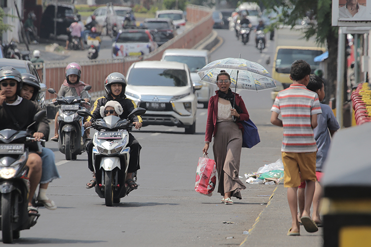 TERIK:&nbsp;Pejalan kaki memakai payung karena terik matahari di Jember. suhunya tembus 35 derajat Celsius.