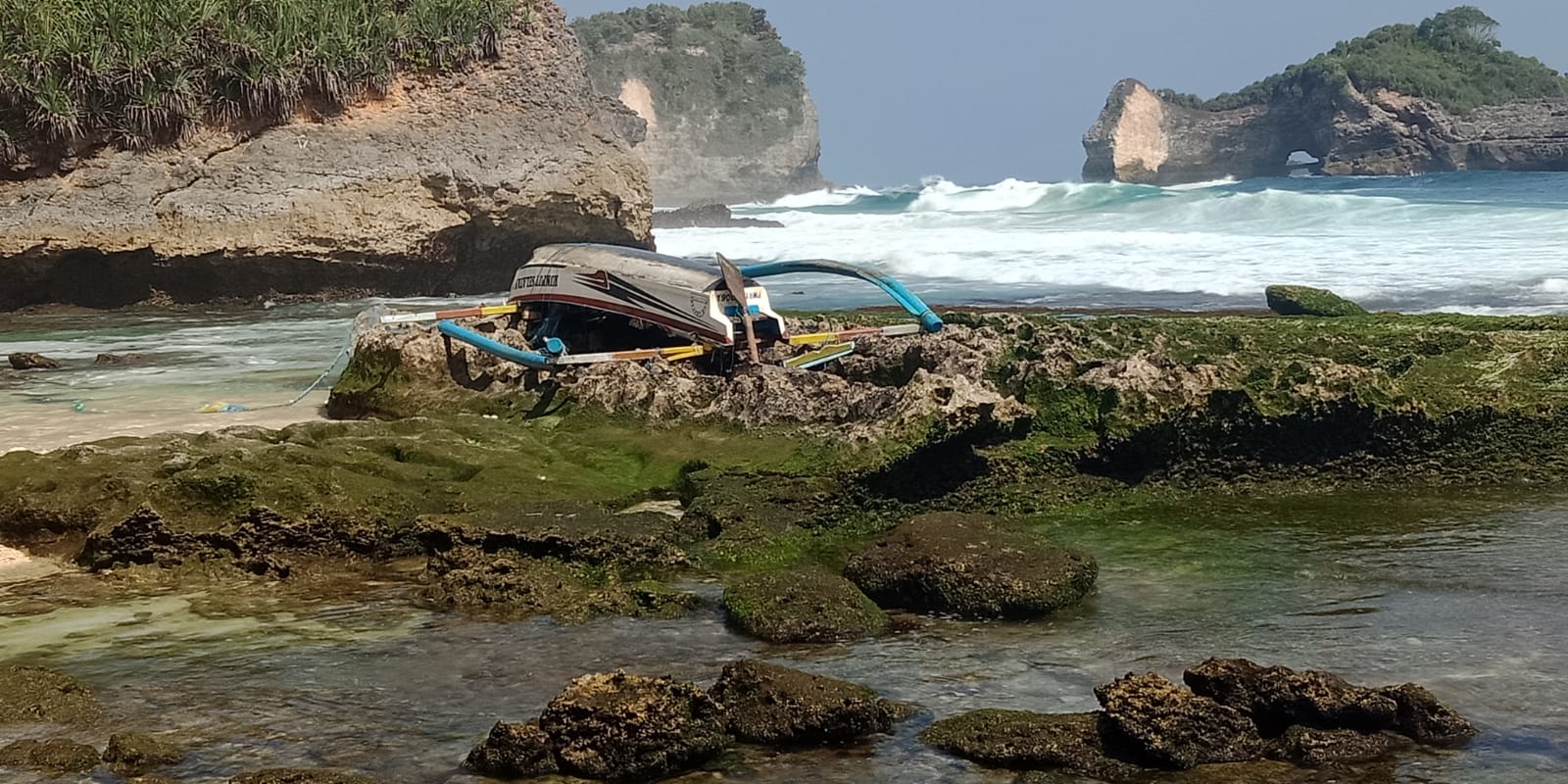 SUSAH DIEVAKUASI: Jukung speed bertuliskan "rumput selatan" masih dalam posisi terbalik di teluk Bendo pulau Nusa Barong. (SATPOLAIR UNTUK RJ)