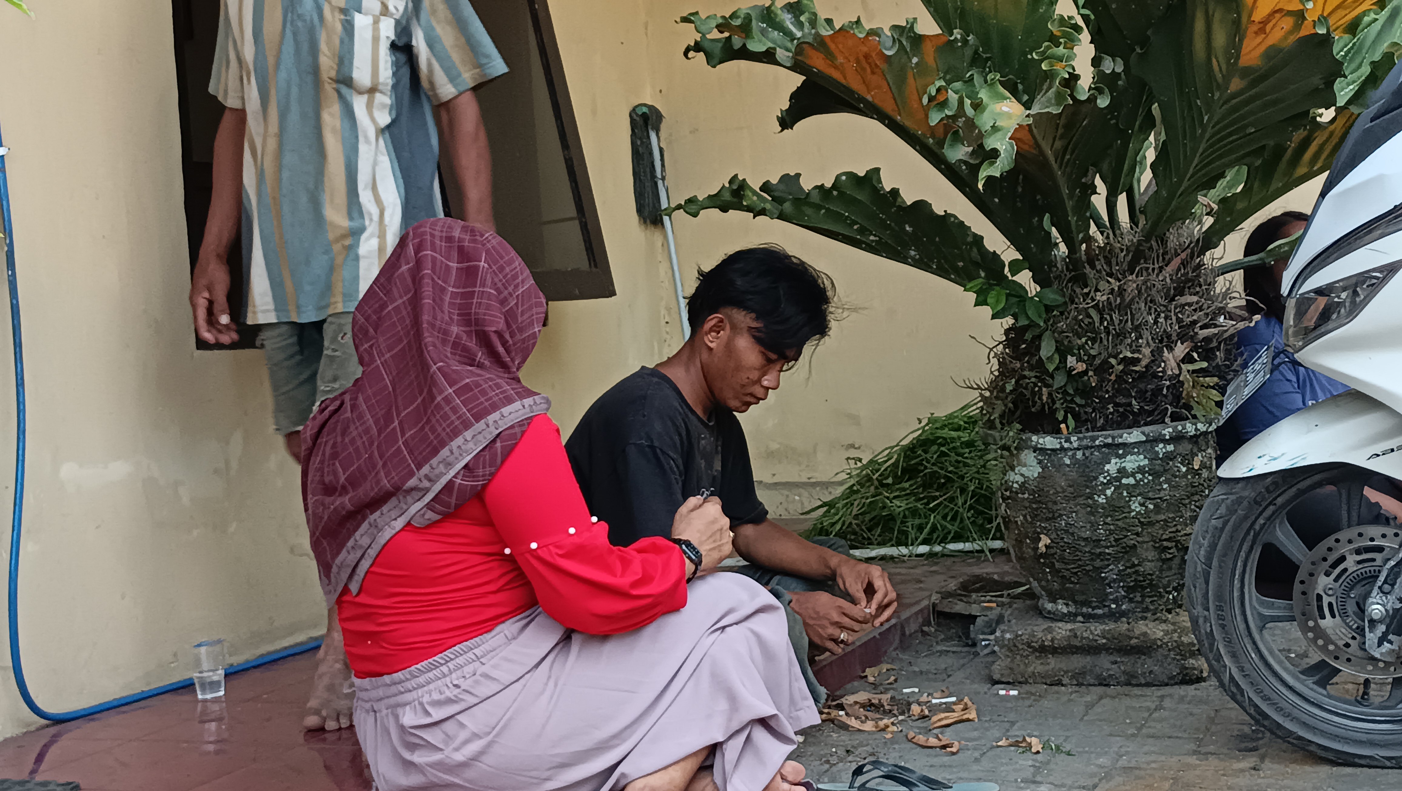LESU: Abdurrohman yang masih menggunakan pakaiannya saat adegan pengeroyokan tampak tertunduk lesu sembari didampingi keluarganya.