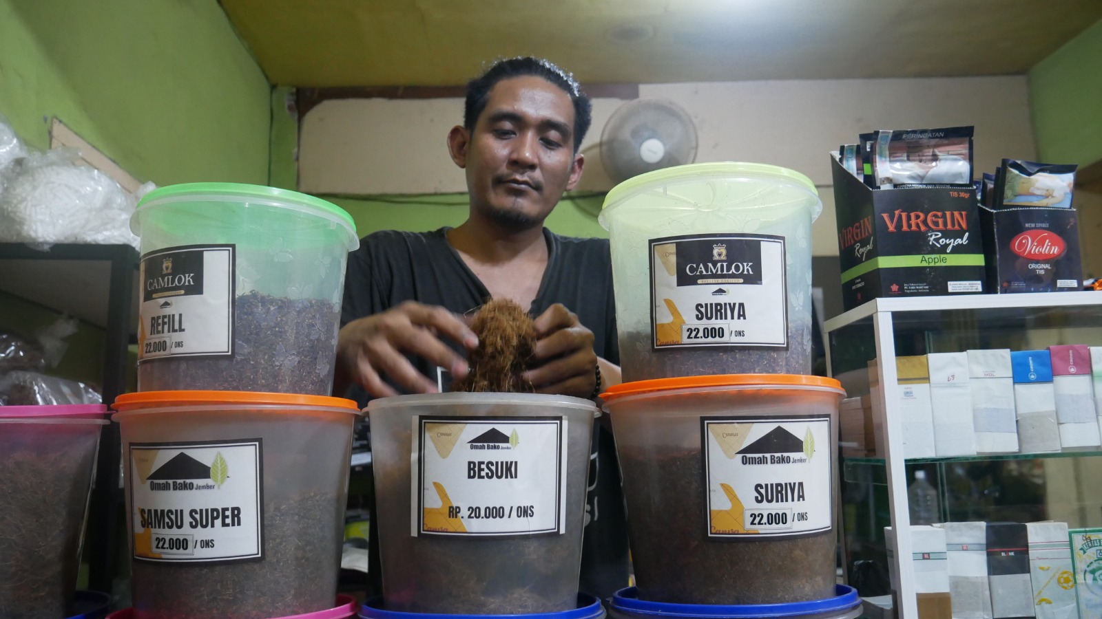 BERTAHAN: Joko Anugrah Purnama Sidi, salah satu penjual tembakau rajangan untuk rokok, saat melayani pembeli di kedai miliknya, Jalan Riau, Sumbersari, beberapa hari lalu.