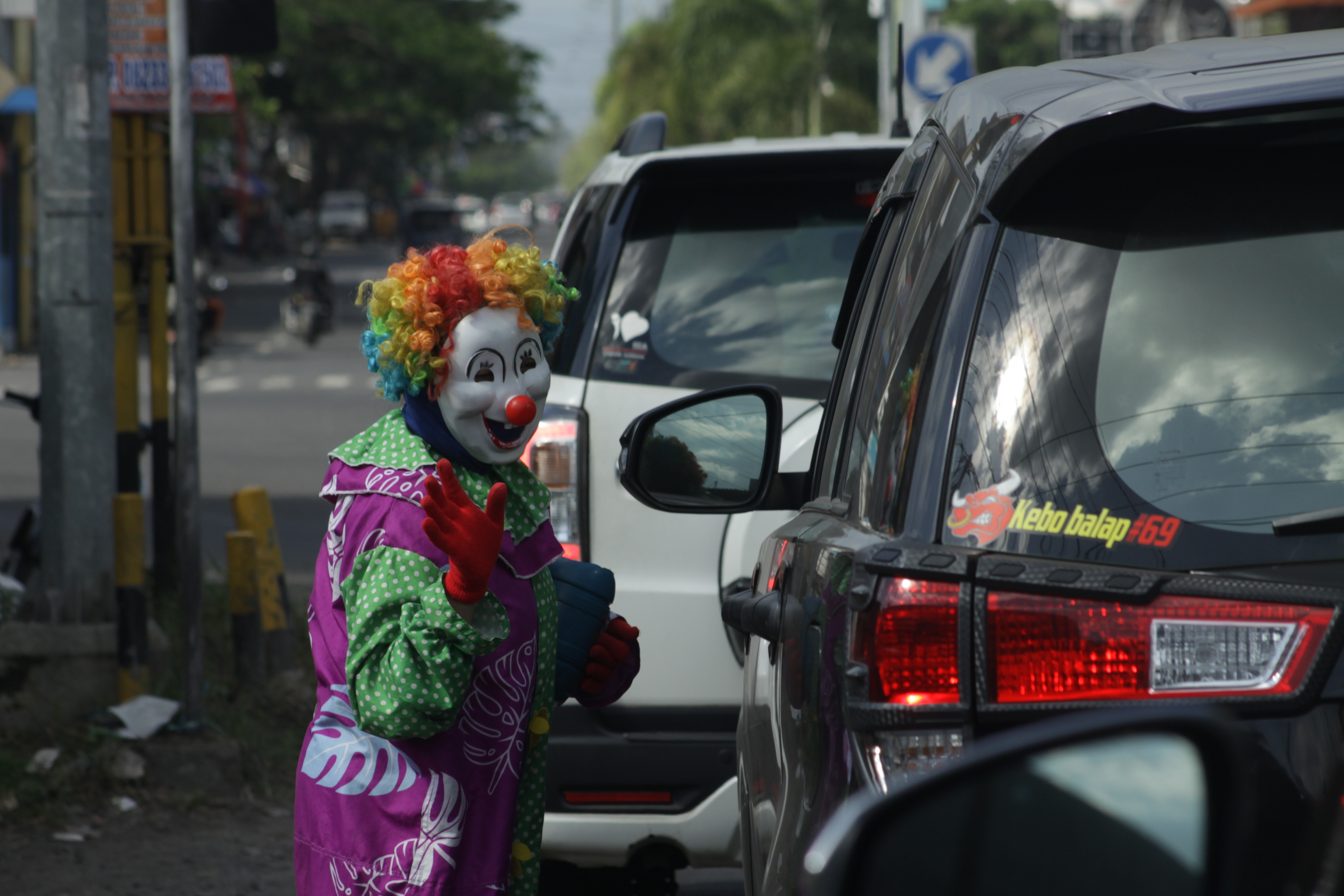 MENYAPA: Badut jalanan ketika melakukan aksinya di lampu lalu lintas wilayah kota Jember.