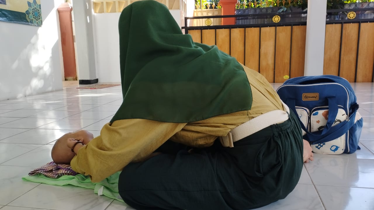 TETAP SEMANGAT: RA, korban pemerkosaan yang dilakukan oleh S, sedang menggantikan pakaian bayinya di sela persidangan di Pengadilan negeri (PN) Jember, Selasa (19/12).
