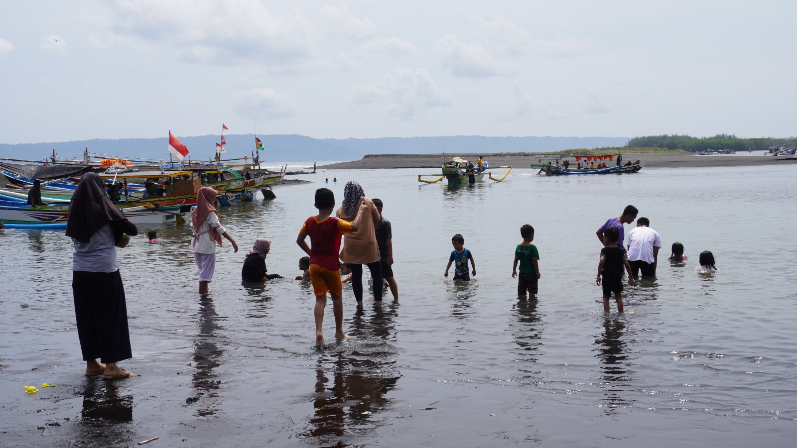 TETAP WASPADA: Pengunjung Pantai Cemara, Dusun Getem, Desa Mojomulyo, Puger, saat mandi di muara sungai, tempat parkir jukung milik nelayan.