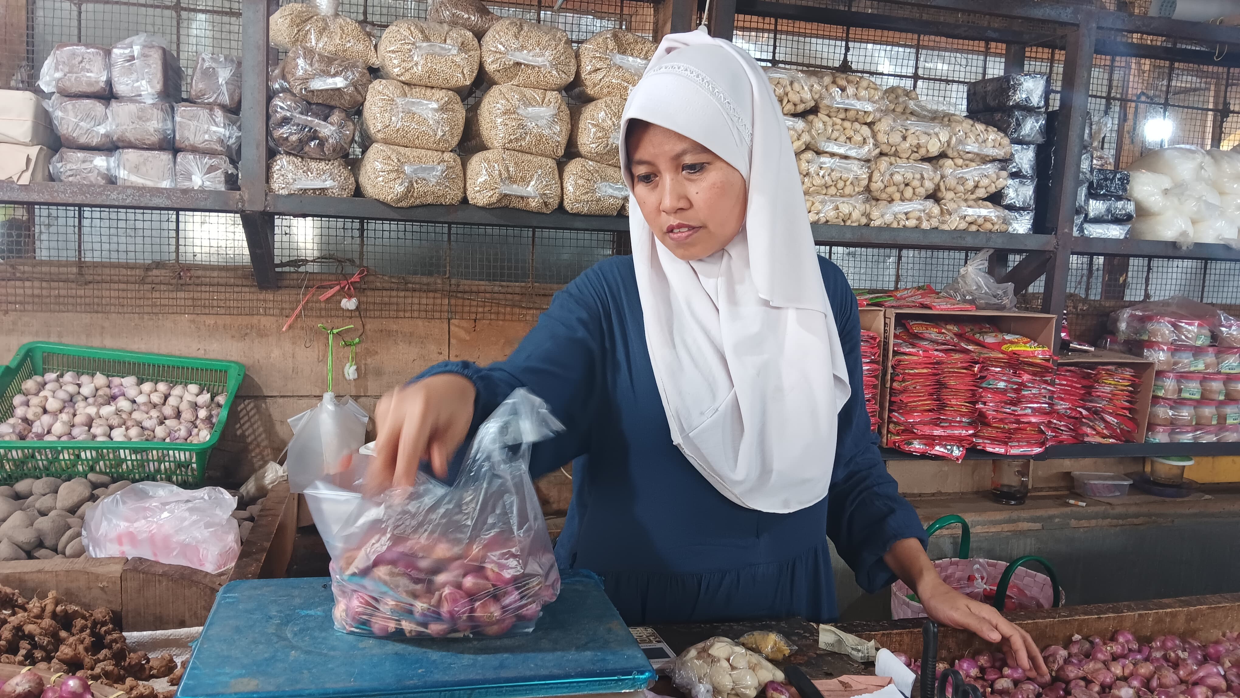 BERDAGANG: Dila, pemilik toko di Pasar Tanjung, Jember, menimbang bawang merah, kemarin (8/1).