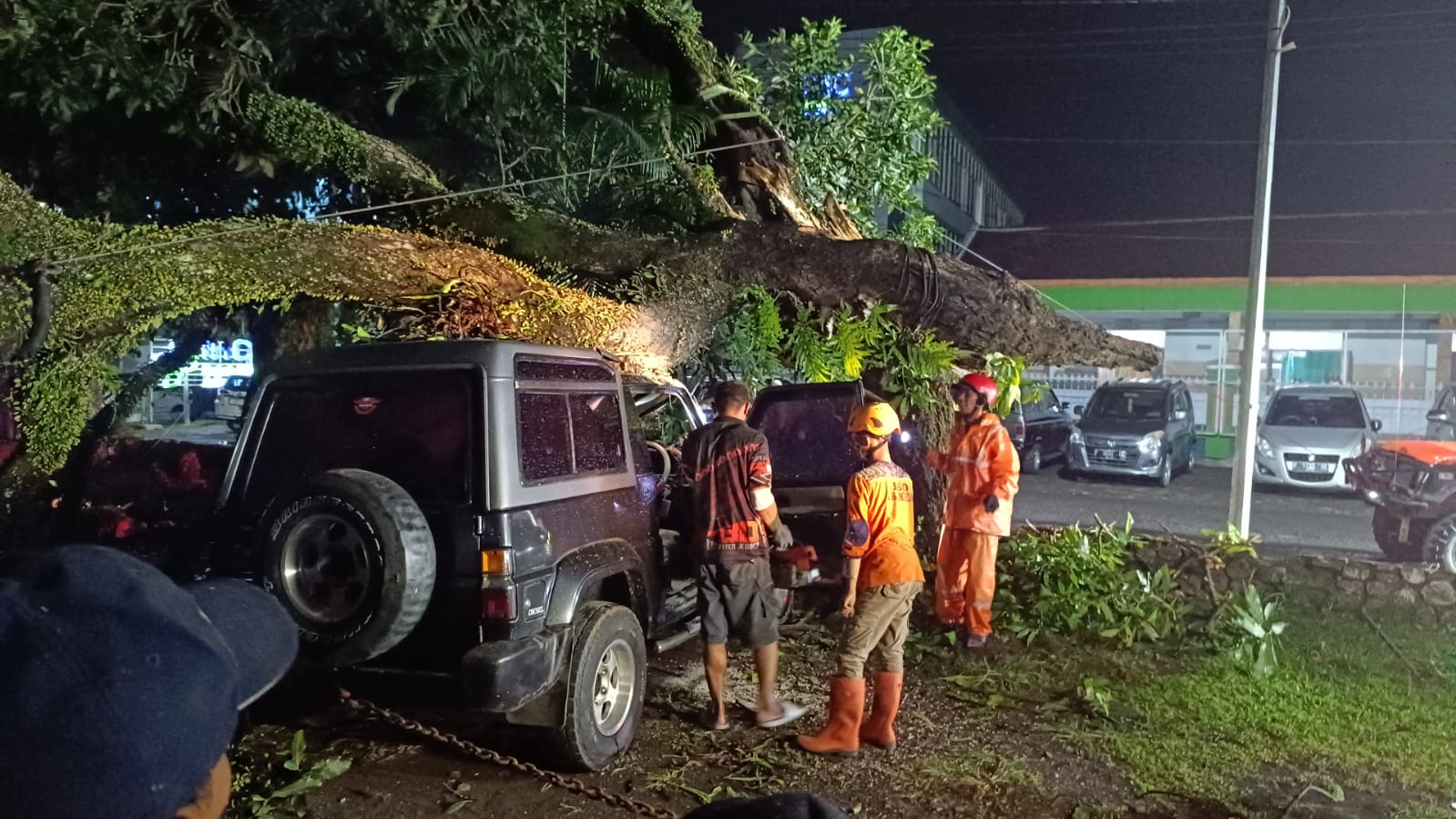 PROSES EVAKUASI: Sebuah mobil Jepp Taff L 1137 XV mengalami rusak parah setelah tertimpa pohon tumbang di halaman parkir RS Kaliwates. (BPBD untuk RJ)