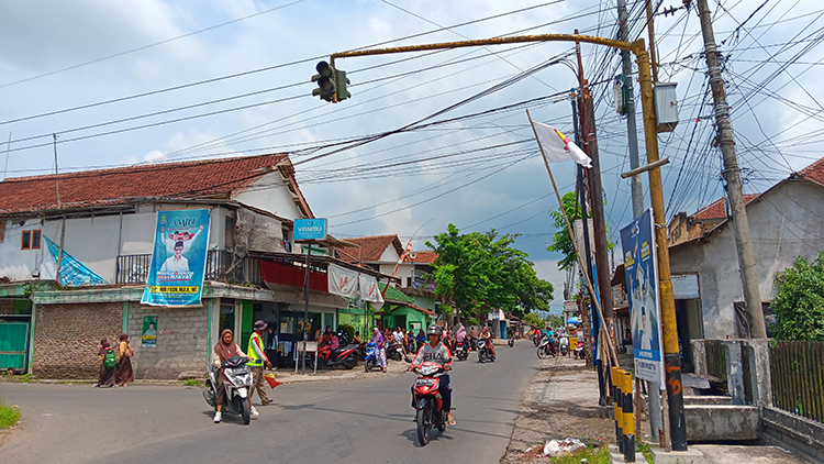 PADAT: Yudi mengatur lalu lintas pengguna jalan dan siswa yang akan menyeberang di daerah Wirowongso, Kecamatan Ajung.