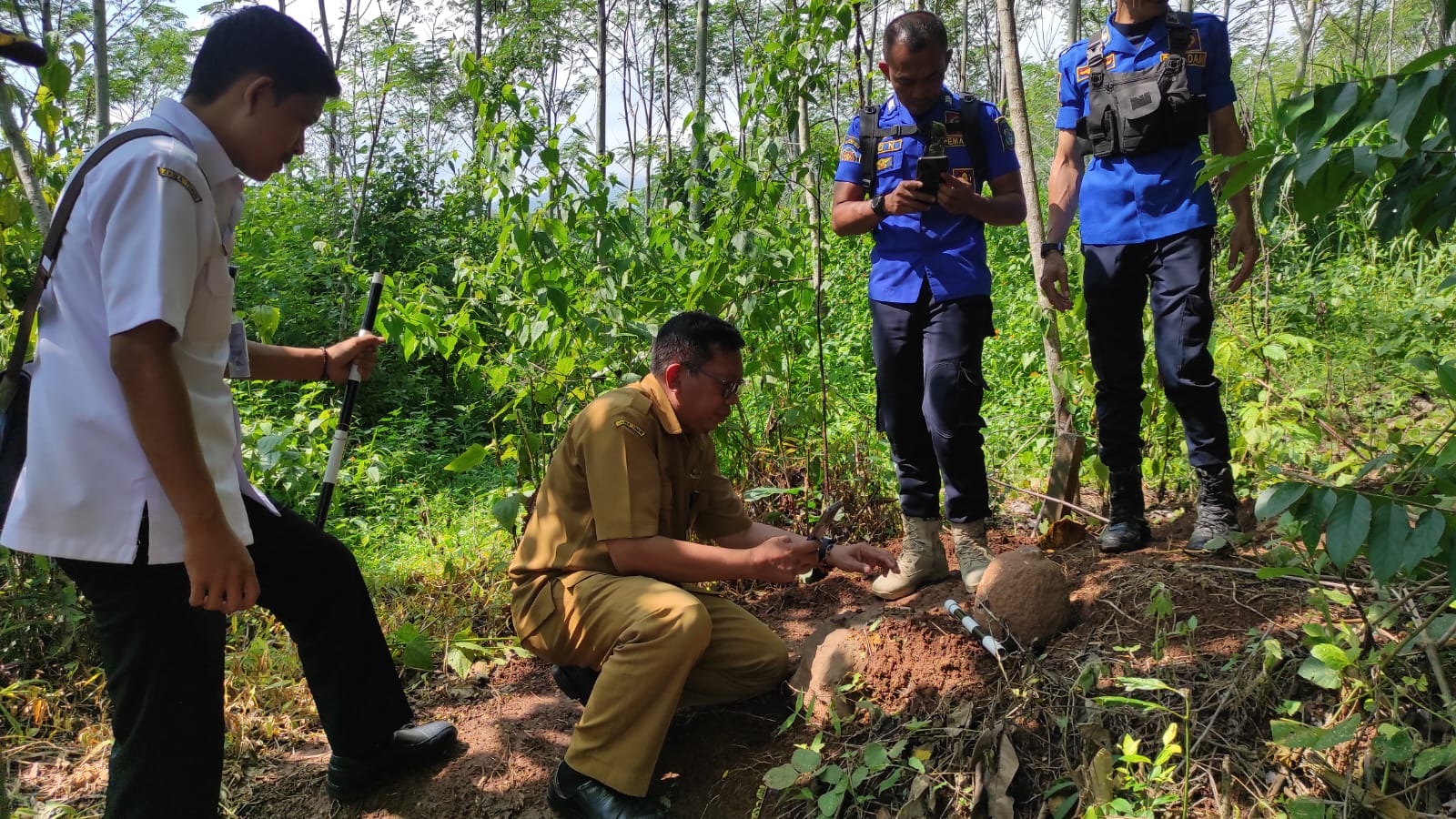 PENYISIRAN: Sejumlah petugas dari Disparbudpora dan Satpol PP mengecek lokasi penemuan batu kenong yang imut.(DISPARBUDPORA BONDOWOSO)