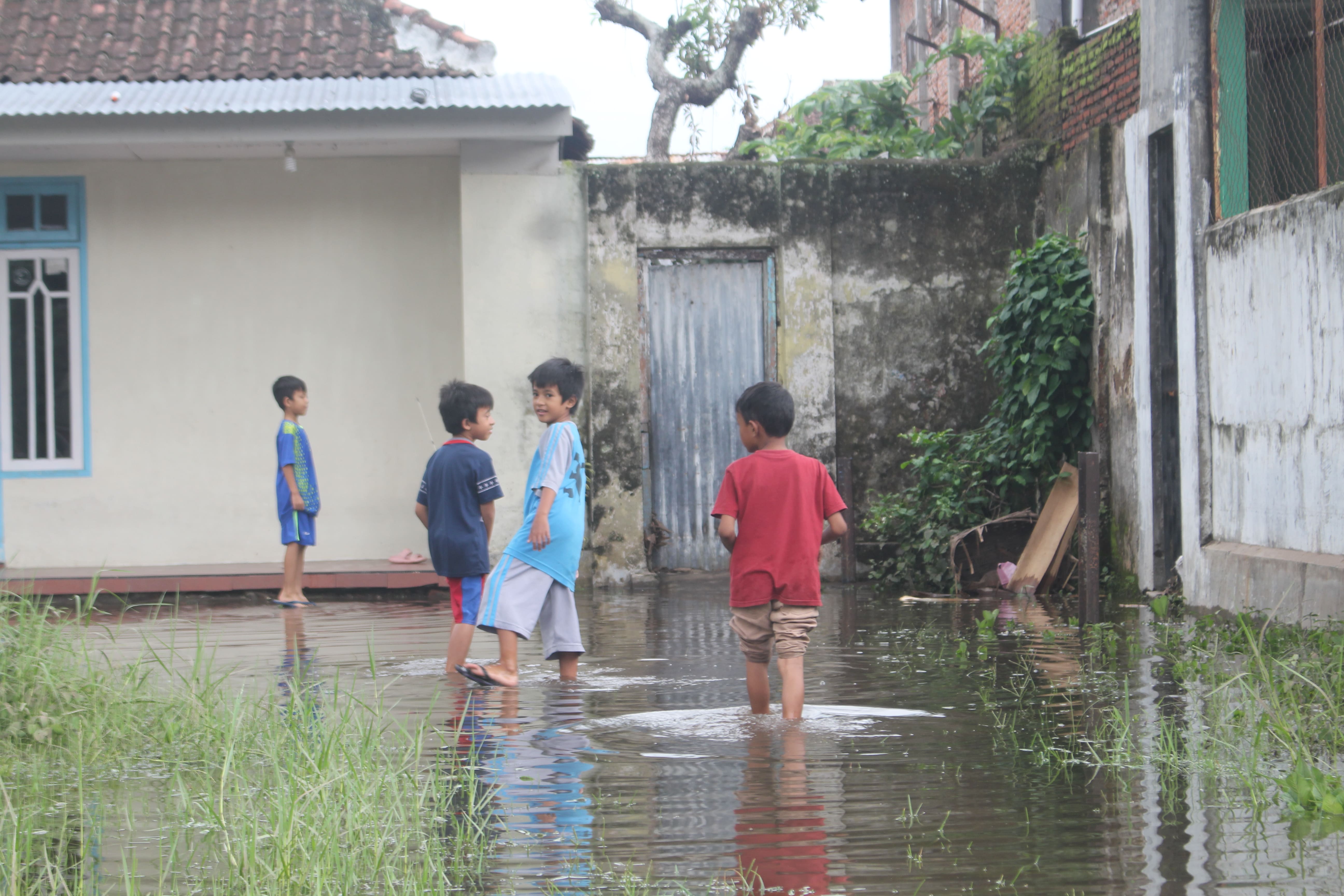 MASIH TERGENANG: Anak-anak bermain air yang masih menggenangi halaman rumah di Kademangan, Bondowoso, Senin (5/2).  (HILMI BASKORO/RADAR IJEN)