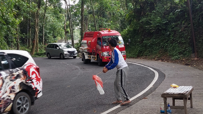 SUKARELAWAN: Tukang awe-awe yang ada di Jalur Gumitir ini sangat membantu para sopir saat memasuki tikungan tajam. (JUMAI/RADAR JEMBER)