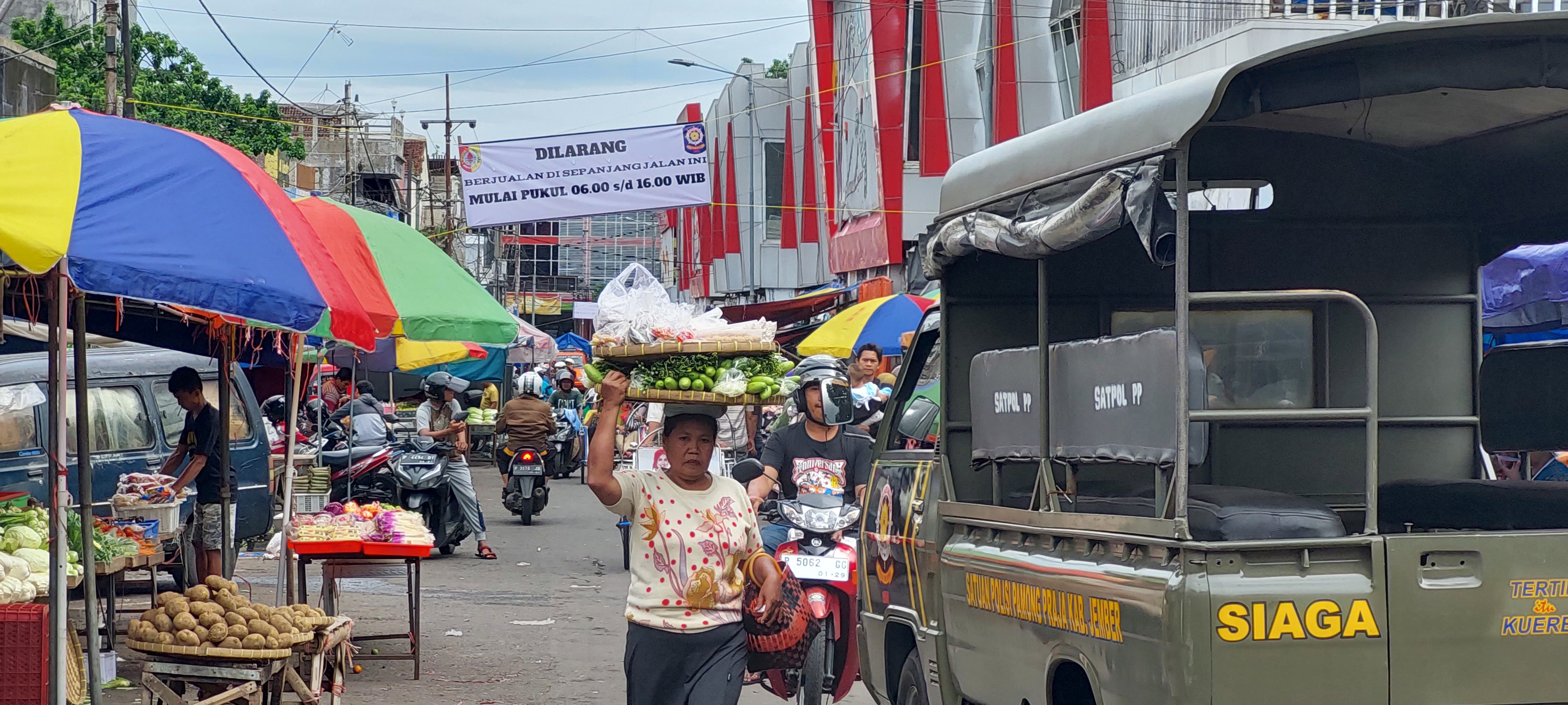 PASANG SPANDUK: Mobil satpol PP bersiaga di Jalan dr Wahidin atau pasar sore Pasar Tanjung untuk menertibkan jam operasional PKL. (JUMAI/ RADAR JEMBER )