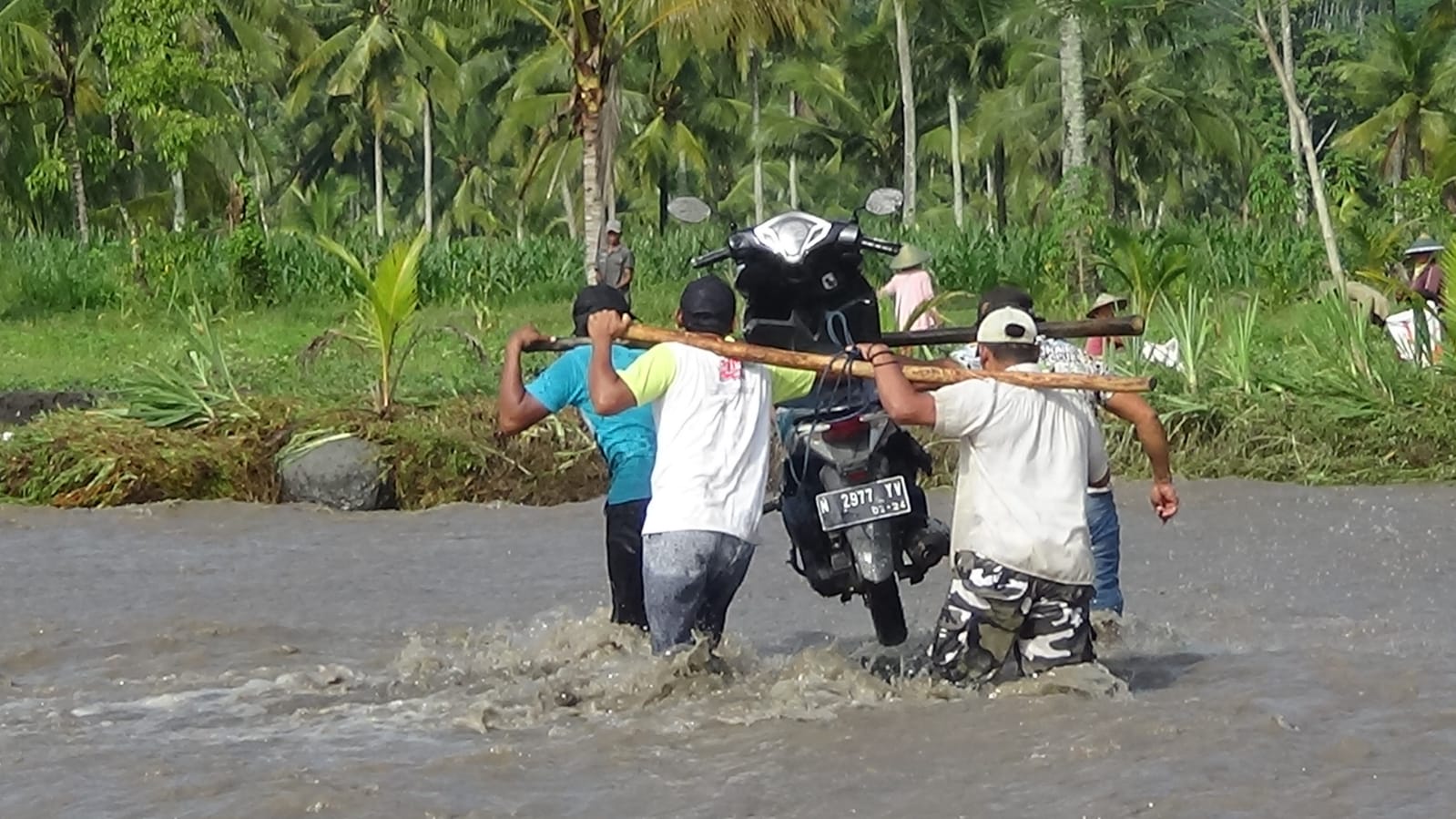 ANGKUT KENDARAAN: Proses penyeberangan kendaraan roda dua melintasi arus deras menggunakan alat seadanya oleh relawan. (HASBI/RJ)