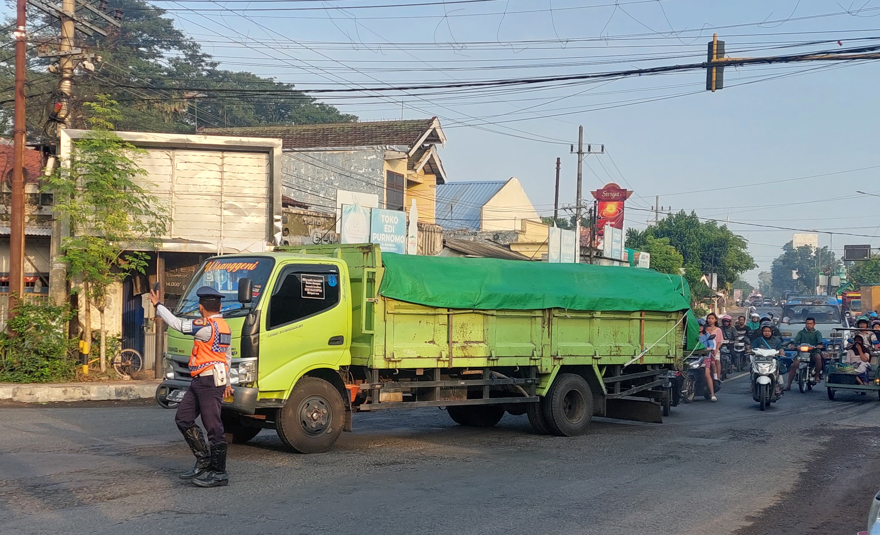 DIARAHKAN: Anggota Dishub Jember mengarahkan sopir truk besar untuk menuju arah Balung di simpang tiga Kaliputih, Desa Rambipuji, Kecamatan Rambipuji, kemarin (21/5). (JUMAI/RJ)