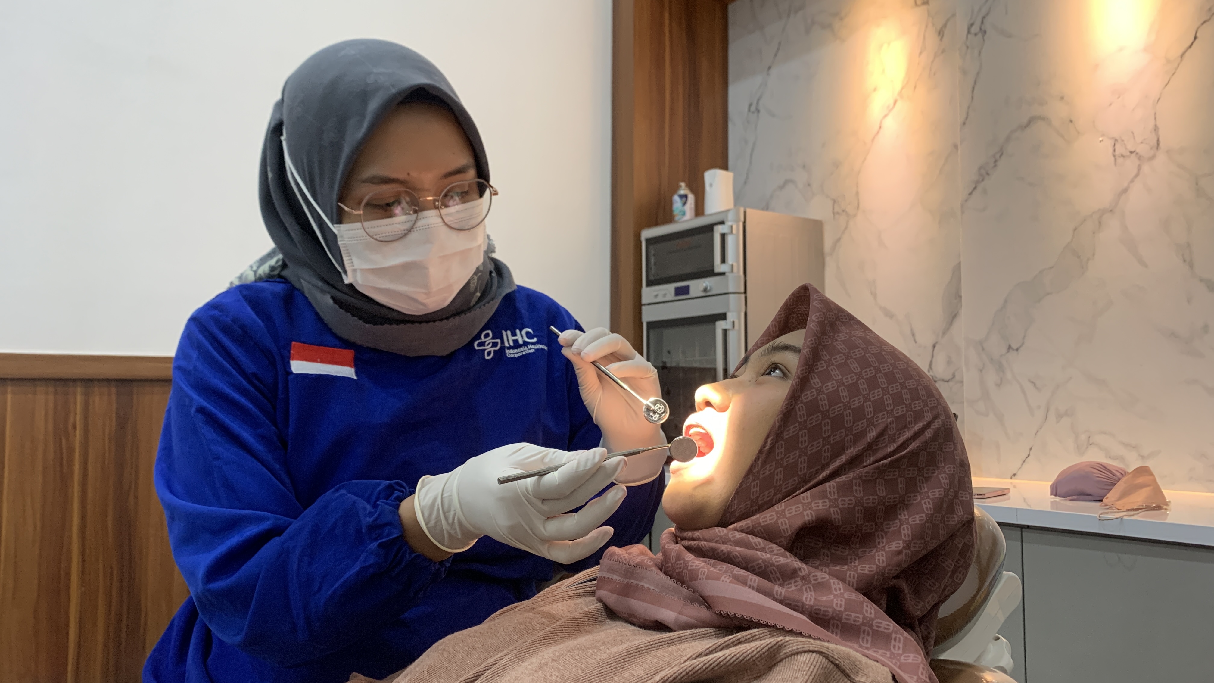 PEMERIKSAAN: Dokter gigi Rolas Dental Care Jember, drg Riskyana Dwi Hendra, melihat kondisi gigi pasiennya. (ILHAM WAHYUDI/RADAR JEMBER)