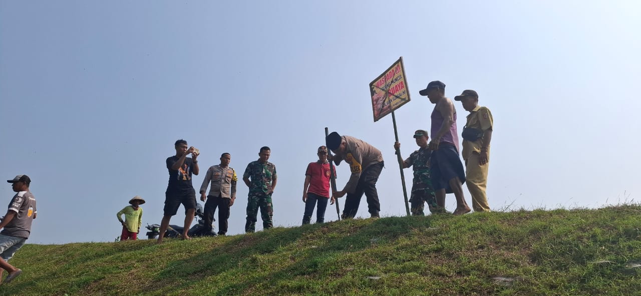 HIMBAUAN: Muspika dan Pemdes Kencong saaat memasang spanduk himbauan di bantaran sungai di Dusun Ponjen, Desa Kencong, Kecamatan Kencong Jumat (14/6).