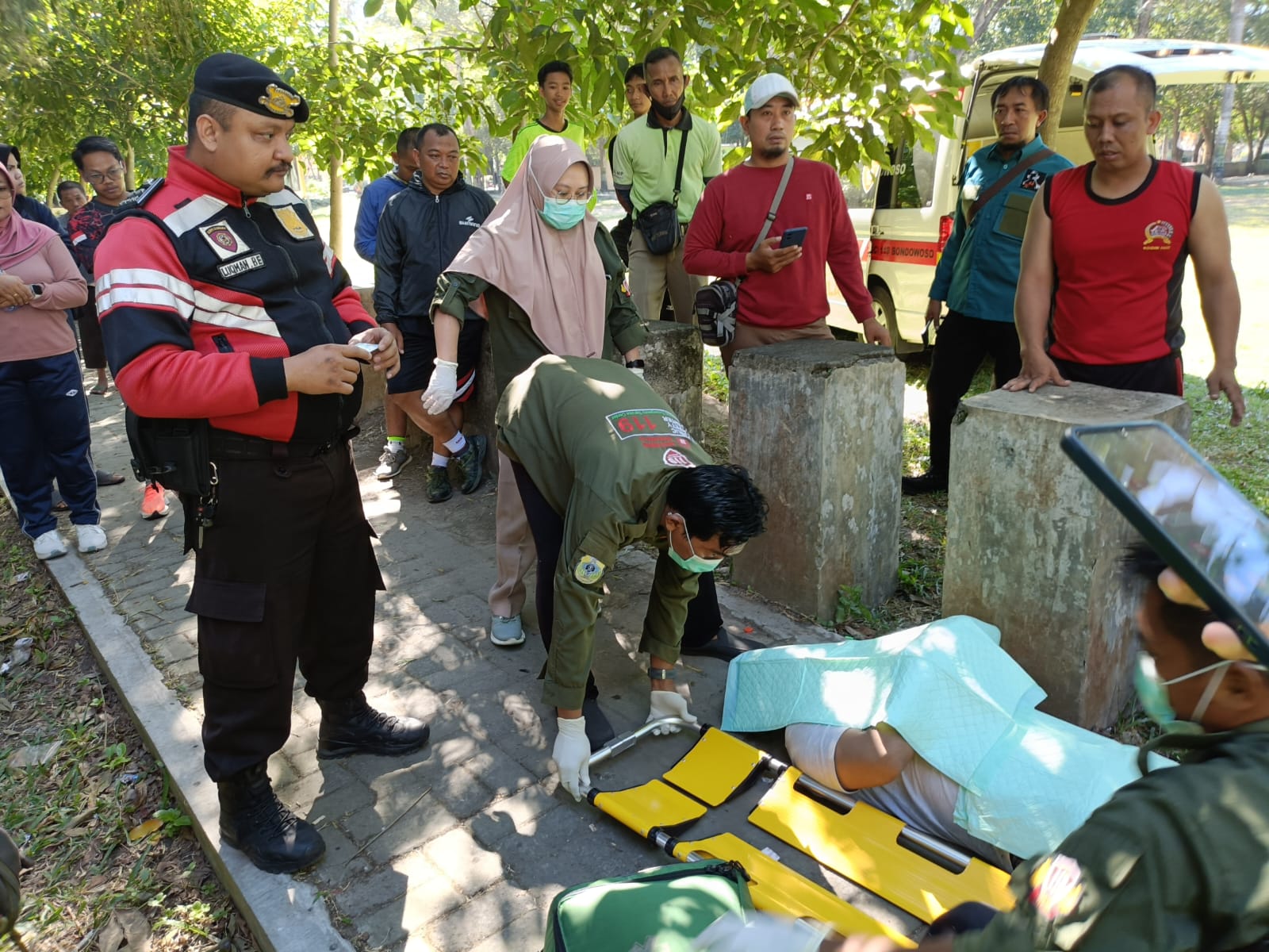 DIEVAKUASI: Polisi bersama pihak lain saat memeriksa pria tergeletak di taman kota, kemarin (27/6).