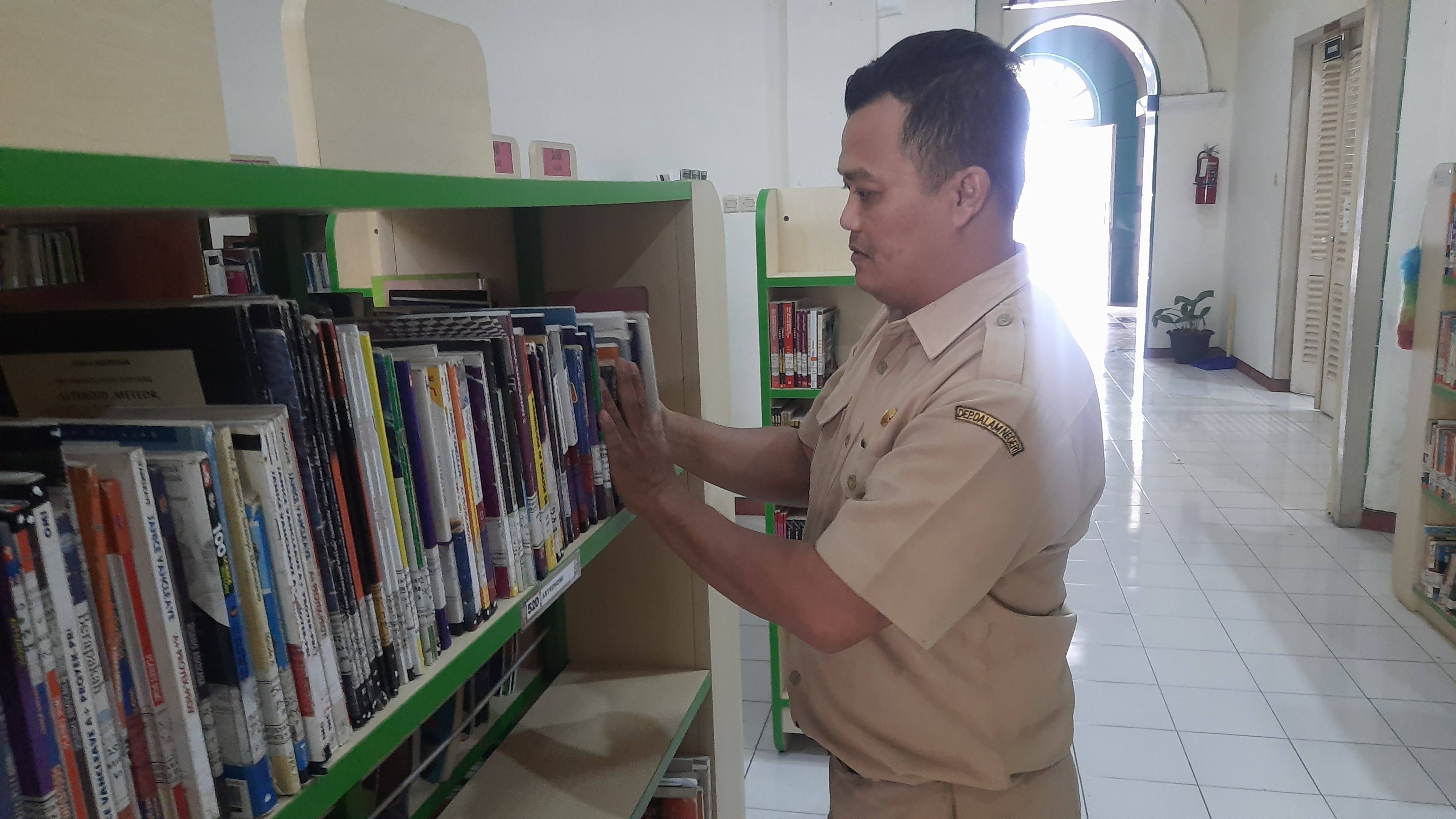 RAPIKAN BUKU: Salah seorang petugas pertuskaan daerah (Perpusda) Bondowoso saat merapikan buku-buku beberapa waktu lalu.