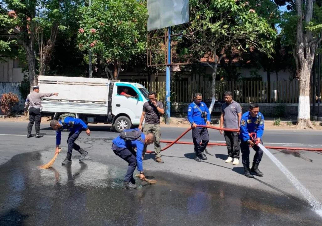 TERUS DIBERSIHKAN: Petugas Damkar Bondowoso saat membersihkan tumpahan solar di Bundaran Nangkaan. Setidaknya lima kali peristiwa serupa terjadi selama Oktober.