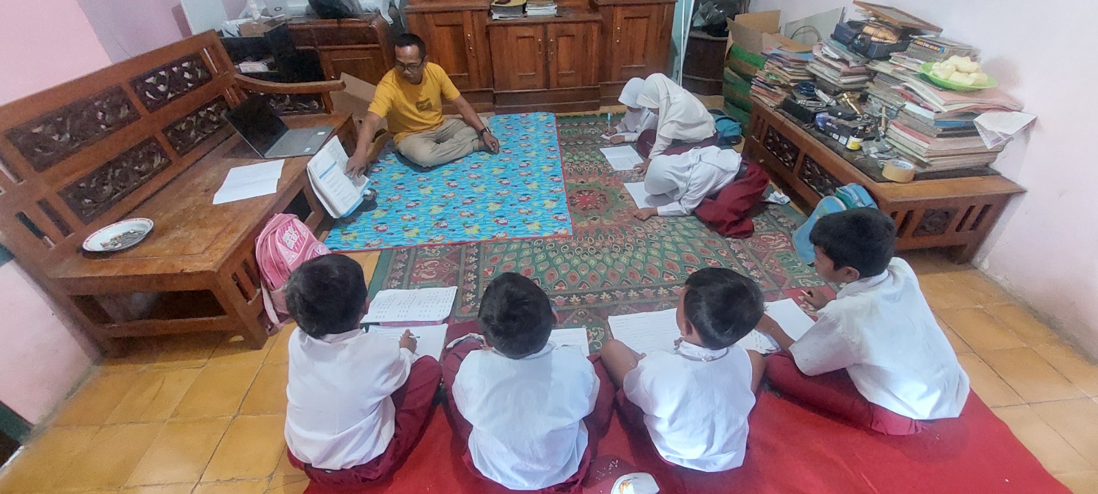 TETAP GIAT: Sekolah diperbaiki, siswa kelas 6 SDN Banjarsari 04 mengikuti KBM di ruang tamu&nbsp; rumah warga.(JUMAI/RADAR JEMBER)