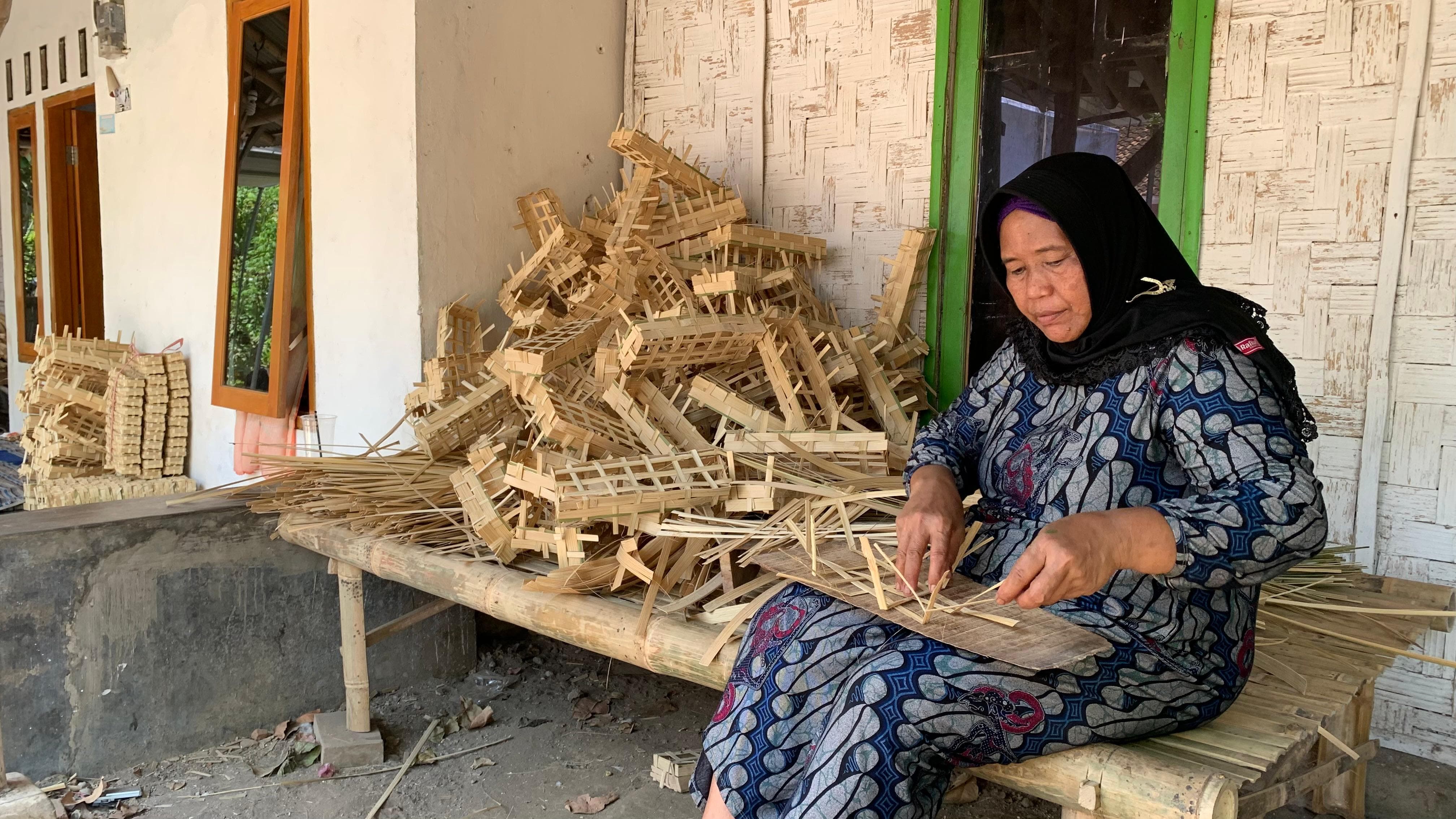 TELATEN: Yaningsih, salah satu perajin rantang ikan di Desa Mlokorejo, Kecamatan Puger, sibuk menganyam di teras rumahnya.(YULIO FA/RADAR JEMBER)