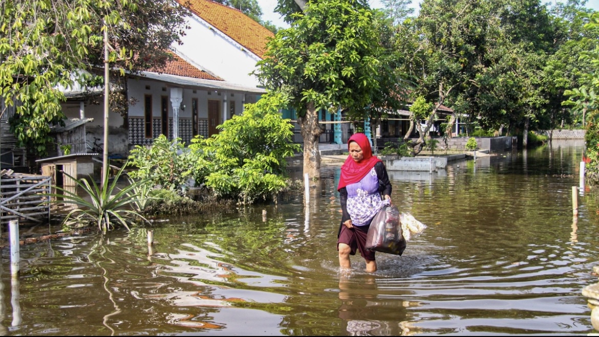 SETELAH: Warga di Dusun Banter Persil menyeberangi banjir di sekitar pekarangan rumah, Jumat. (MUHAMMAD HASBI/RAME)