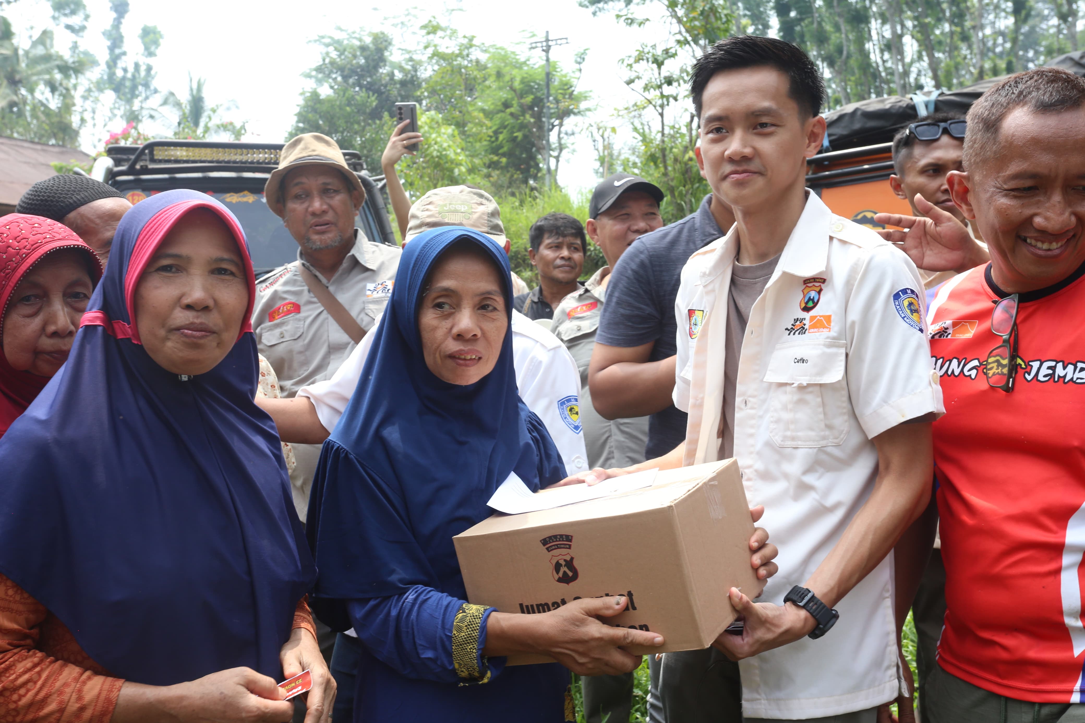 KEMANUSIAAN: Kapolres Jember AKBP Bayu Pratama Gubunagi dan Ketua Raung 4x4 Jember Cefiro Clan Chiu menyerahkan bantuan paket sembako kepada warga Dusun Klungkung, Sabtu
