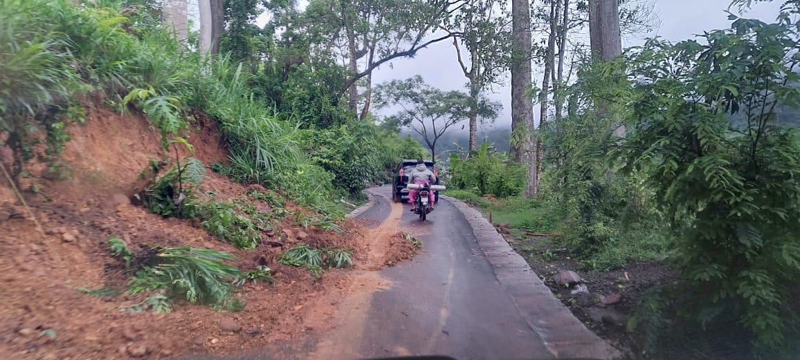 LONGSOR: Tanah yang longsor dari tebing hingga ke jalan aspal menuju pantai Bandealit dan kondisinya cukup licin. (JUMAI/RJ)