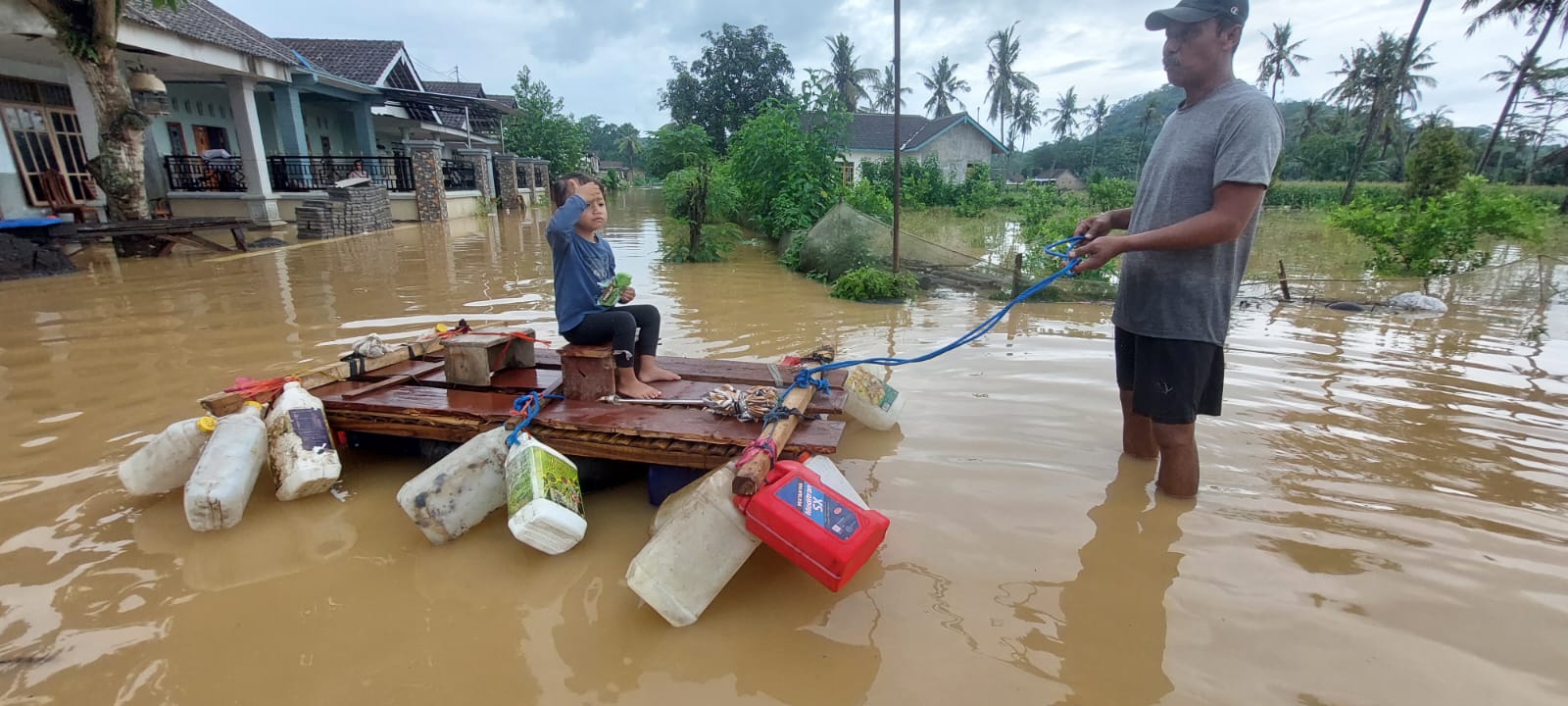 BIKIN RAKIT: Jarot, warga Gg. IV Dusun Kraton, Desa Wonoasri membuat getek rakit dari bahan jeriken bekas untuk cucunya saat terjadi banjir susulan, Minggu (1/12). (JUMAI/RJ)