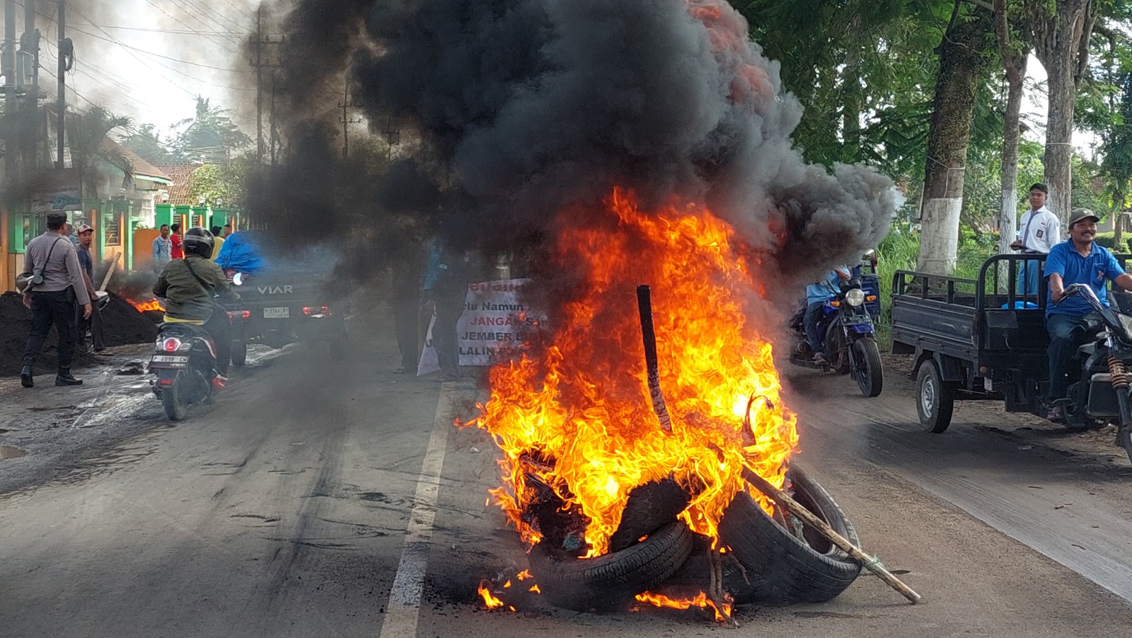 BAKAR BAN DI JALAN: Warga membakar ban di depan Kantor Balai Desa Curahmalang, Kecamatan Rambipuji, sebagai bentuk protes rusaknya jalan provinsi jurusan Rambipuji&ndash;Puger Jember, Selasa (3/12).