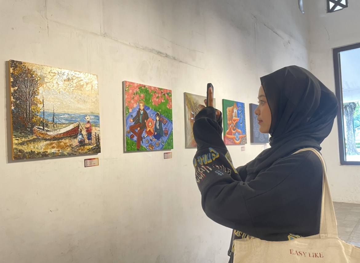 KAGUM: Salah satu pengunjung pameran seni rupa di Lumajang terpaku dengan keindahan karya yang dipamerkan.(ADE APRYANIS/RAME)