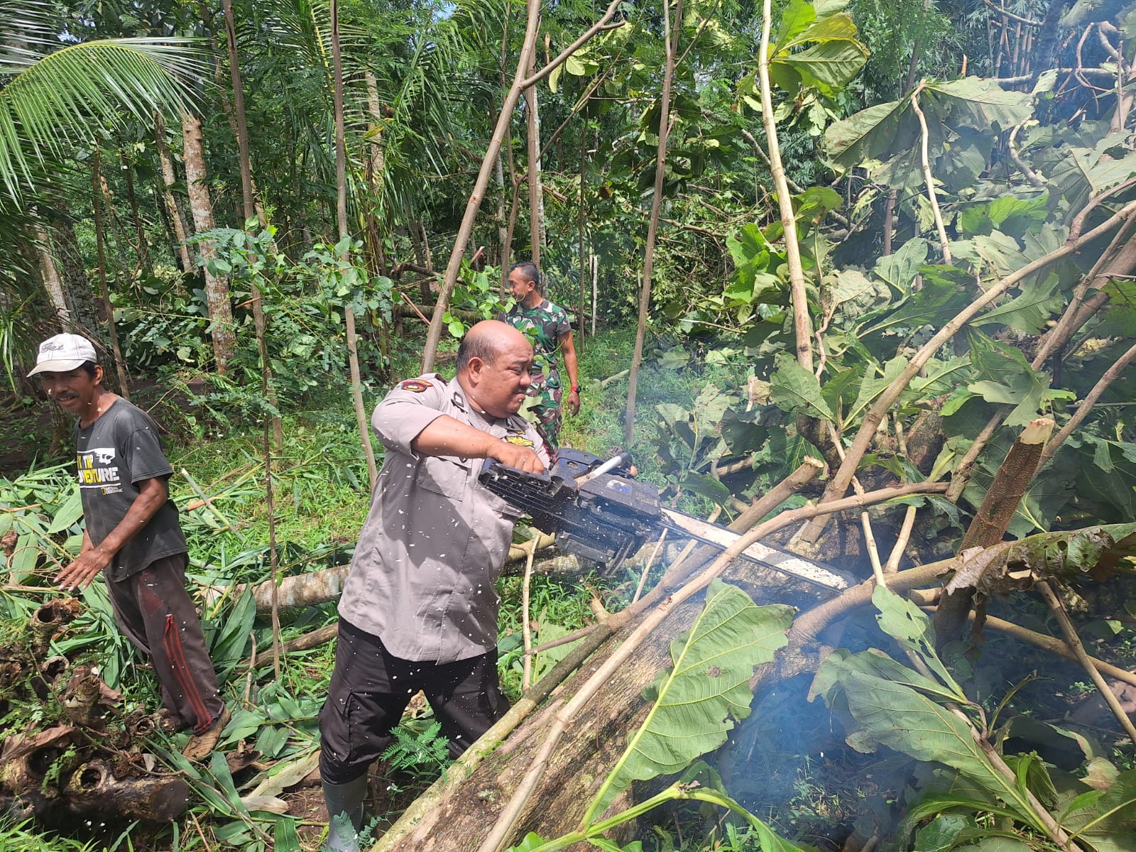 KERJA BAKTI: Anggota Polsek dan Koramil bersama warga saat kerja bakti saat memotong ranting pohon yang menimpa rumah warga.