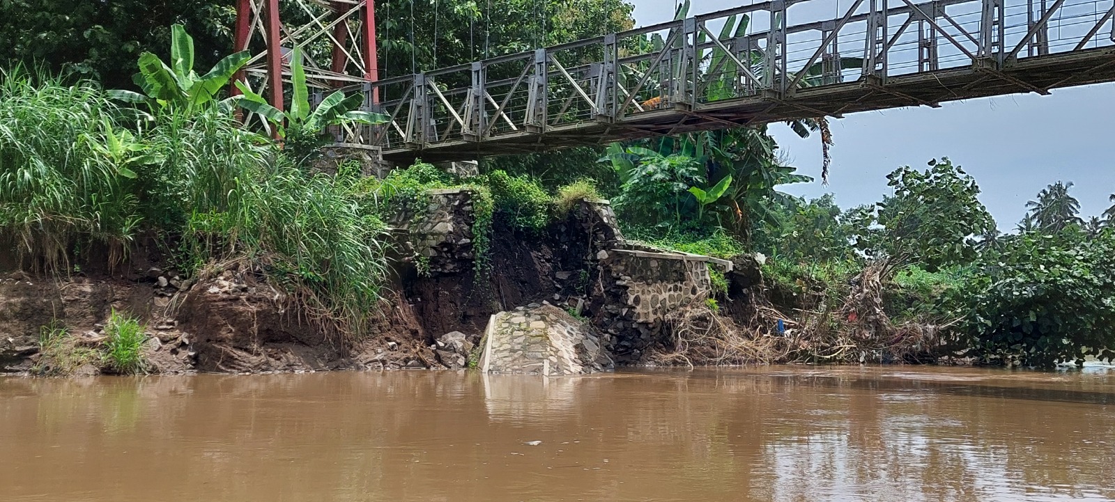 AMBROL: Fondasi jembatan gantung di sisi timur ambrol setelah tergerus arus Kali Mayang yang beberapa kali banjir, kemarin.