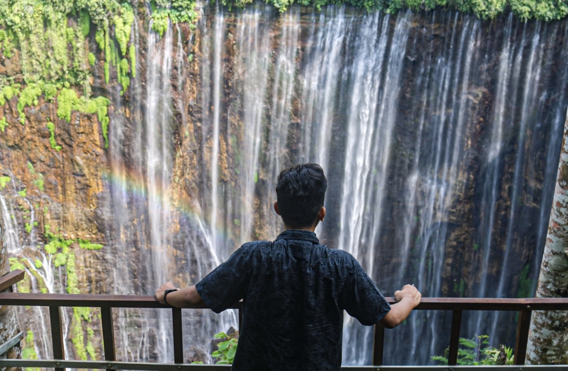 MEMUKAU: Salah satu pengunjung menikmati keindahan air terjun Tumpak Sewu dari Grojogan Sewu di Desa Sidomulyo, Kecamatan Pronojiwo.(MUHAMMAD HASBI/RAME) 