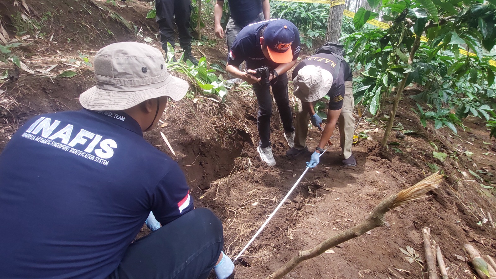 OLAH TKP: Polisi menyelidiki lokasi tempat korban dikubur dan mengukur lubang kuburan yang dalamnya hanya selutut orang dewasa, di perkebunan Desa Garahan, Kecamatan Silo, kemarin. (JUMAI/RJ)
