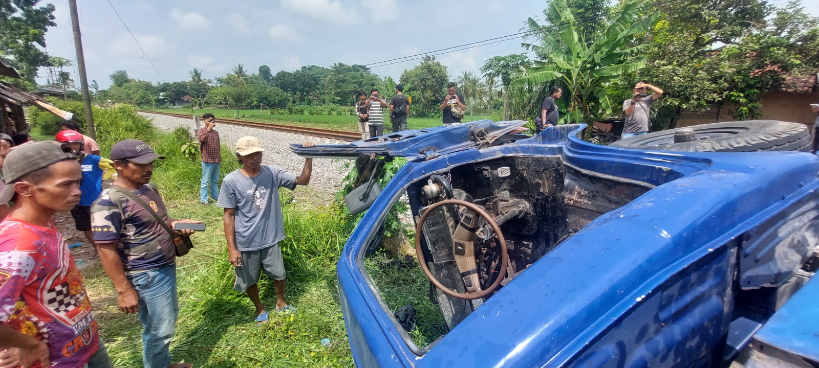 TERPENTAL: Sejumlah warga melihat truk yang terguling setelah ditabrak Kereta Api Logawa, di Kelurahan Baratan, kemarin.