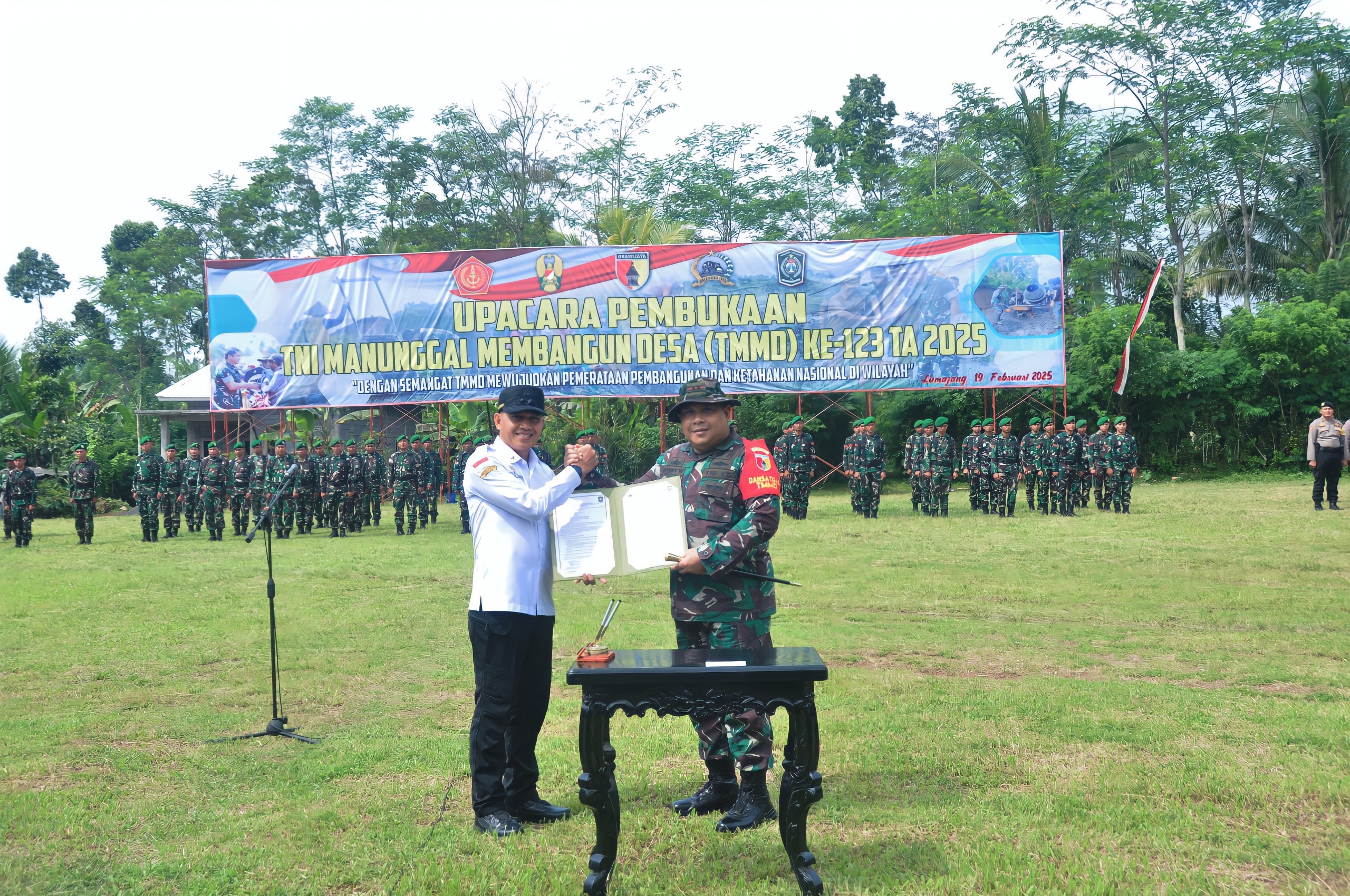SERAHKAN: Sekertaris Daerah Lumajang Agus Triyono (kiri) menyerahkan surat penandatanganan berita acara proyek TMMD 123 kepada Dandim 0821/Lumajang Letkol Inf Ronyy Wijaya Koesuma (kanan).