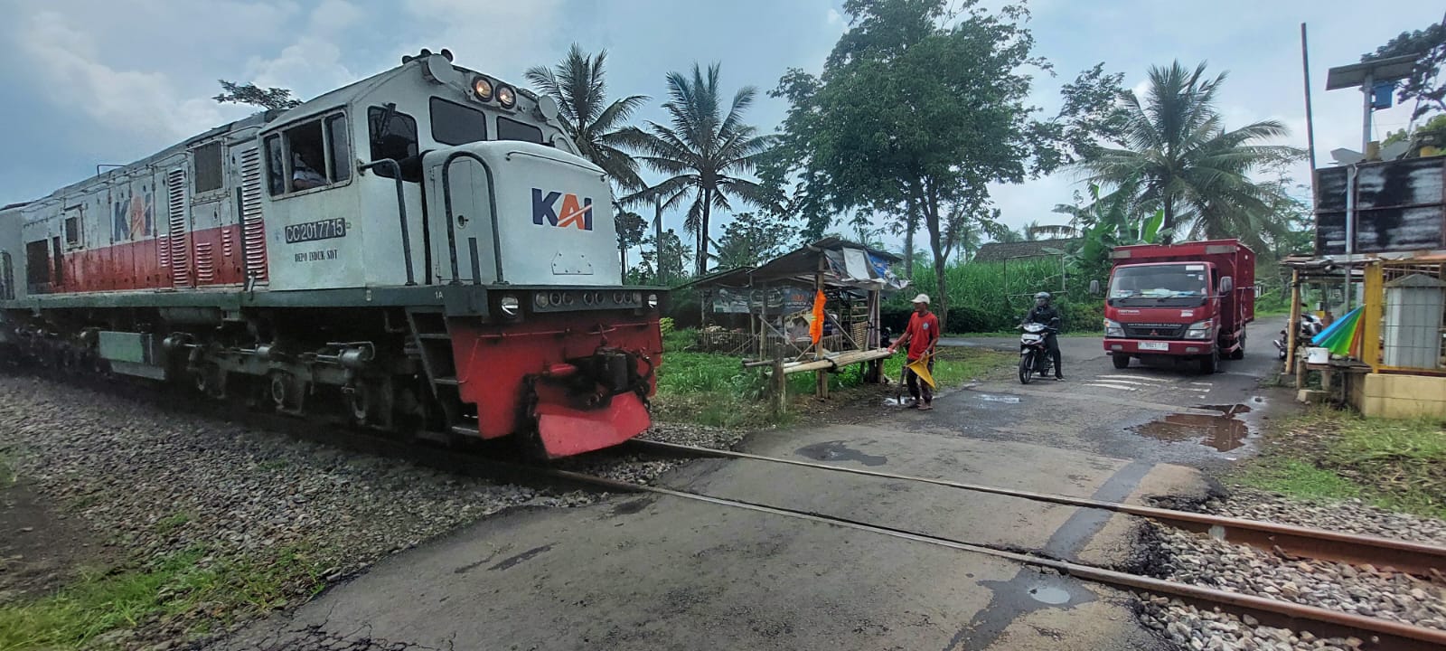TANPA PAMRIH: Samijan, 70, relawan penjaga lintasan kereta api tanpa palang pintu, menghadang pengendara mobil, di Dusun Krajan Kidul, Desa Yosorati, Kecamatan Sumberbaru, Selasa (18/2).