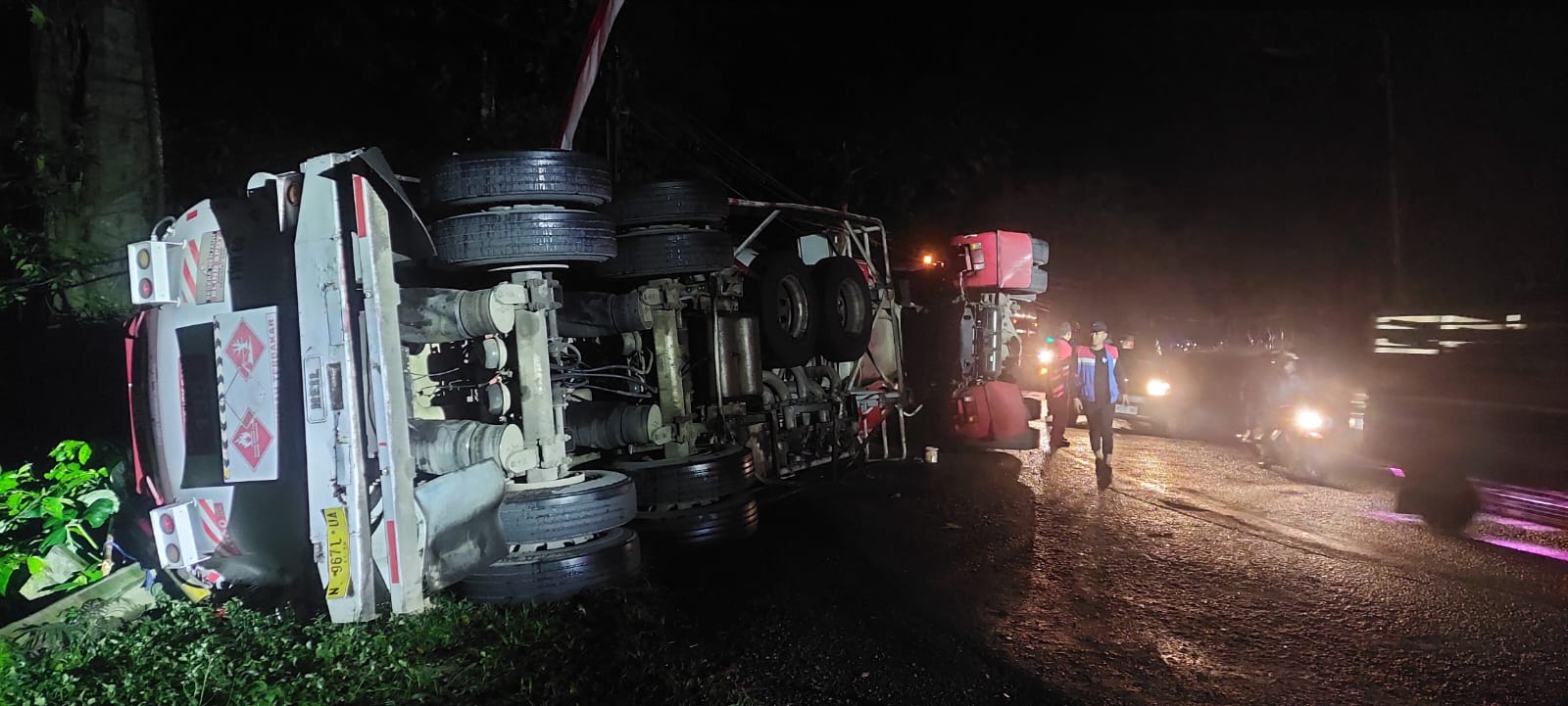 TERGULING: Kondisi truk tangki yang terguling di jalur Gumitir tadi sore. Hingga malam ini truk masih belum di evakuasi secara total. (JUMAI/RADAR JEMBER)