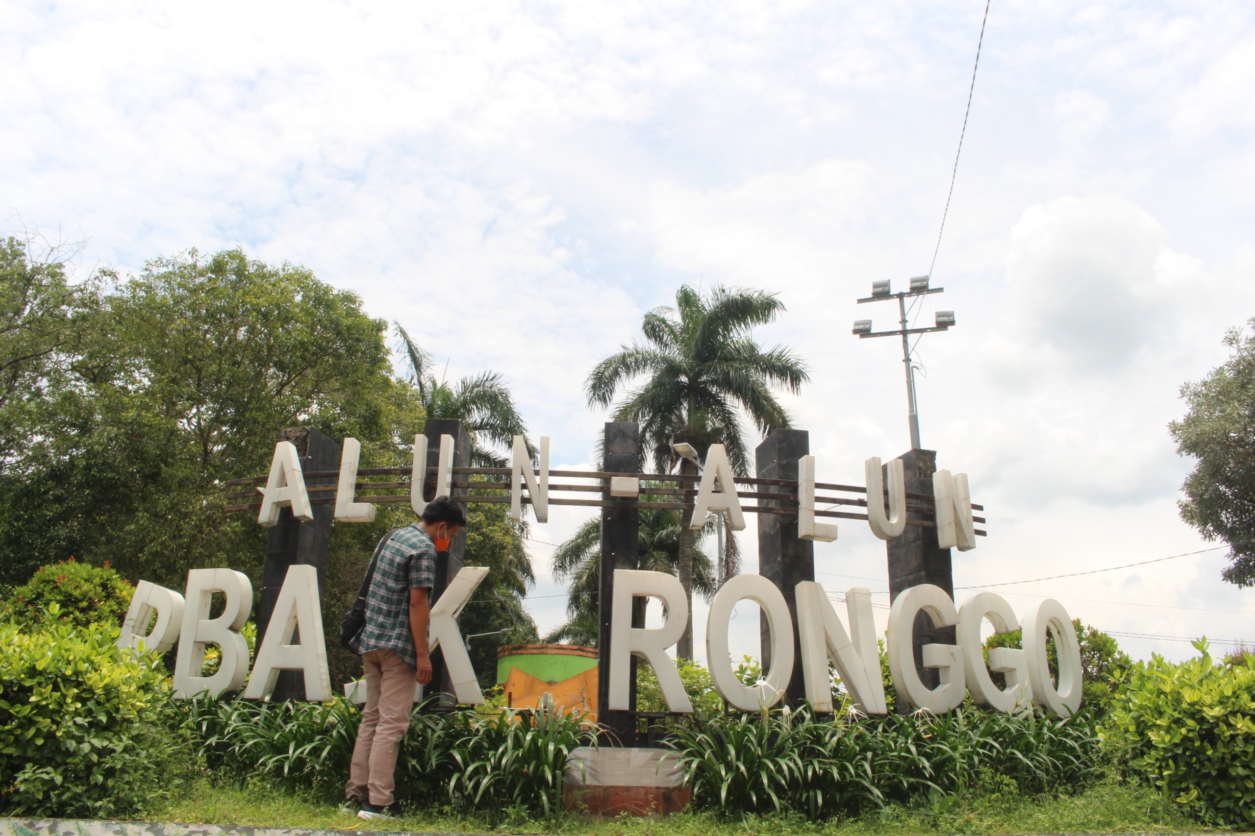 BELUM DIPERBAIKI: Salah seorang warga melihat kondisi papan nama alun-alun RBA Ki Ronggo, kemarin. (ILHAM/RJ)